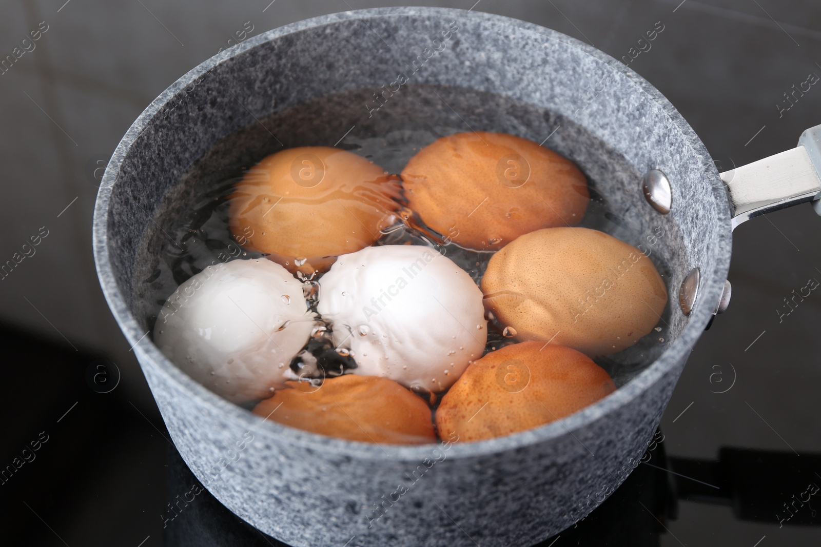 Photo of Chicken eggs boiling in saucepan on electric stove, closeup