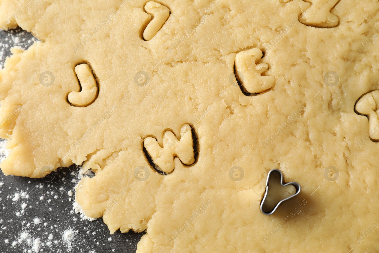 Photo of Making shortcrust pastry. Raw dough and cookie cutter on grey table, top view