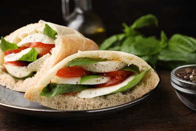Photo of Delicious pita sandwiches with mozzarella, tomatoes and basil on wooden table, closeup