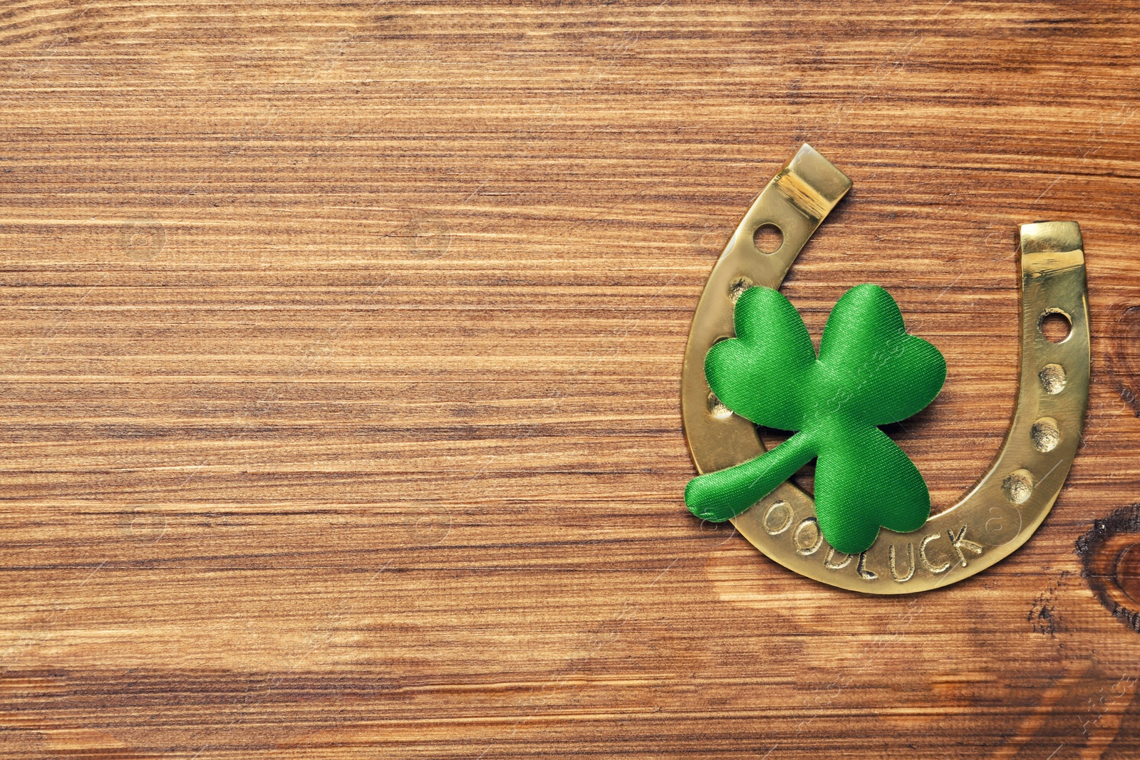 Photo of Decorative clover leaf and horseshoe on wooden background, flat lay with space for text. St. Patrick's Day celebration