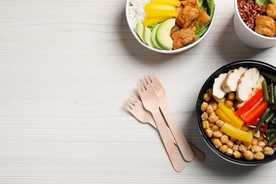 Different healthy meals in takeaway containers and wooden forks on white table, flat lay. Space for text