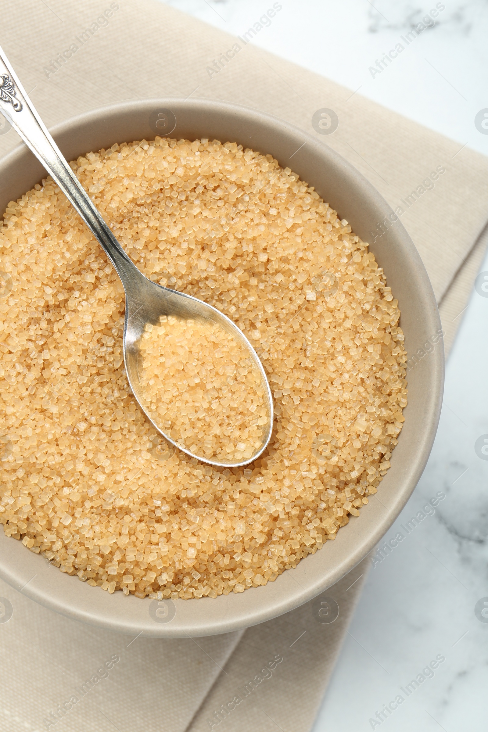 Photo of Brown sugar in bowl and spoon on white table, top view