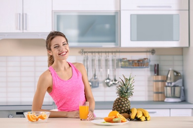 Photo of Woman with glass of orange juice on table in kitchen. Healthy diet