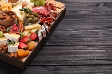 Photo of Assorted appetizers served on black wooden table. Space for text
