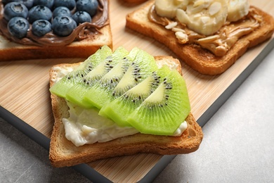 Photo of Toast bread with kiwi on wooden board, closeup