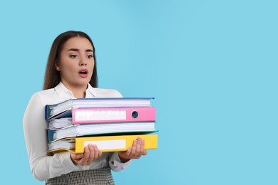 Stressful woman with folders on light blue background, space for text