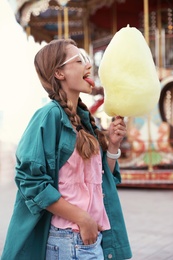 Photo of Young woman with cotton candy in amusement park