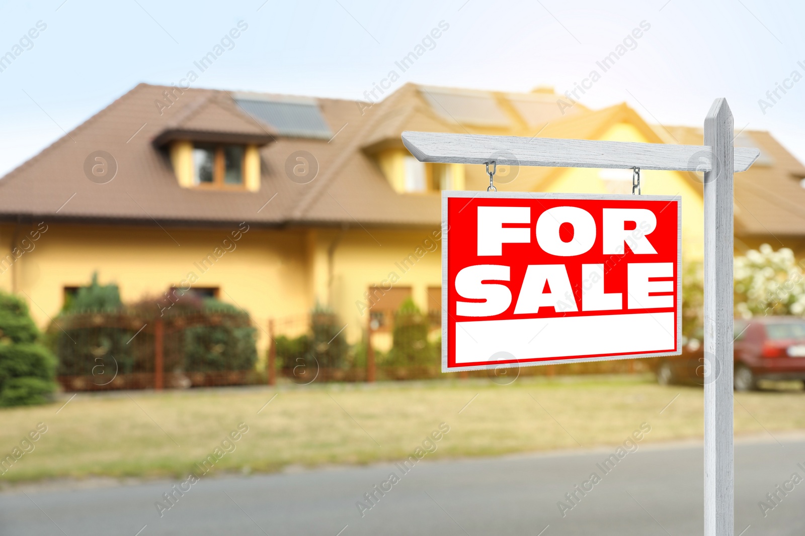 Image of Sale sign near beautiful house outdoors. Red signboard with words