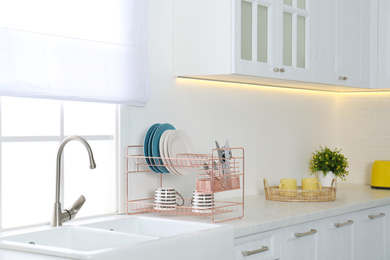 Clean dishes on drying rack in modern kitchen interior