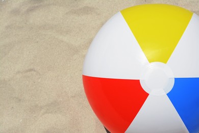 Photo of Colorful beach ball on sand, top view. Space for text