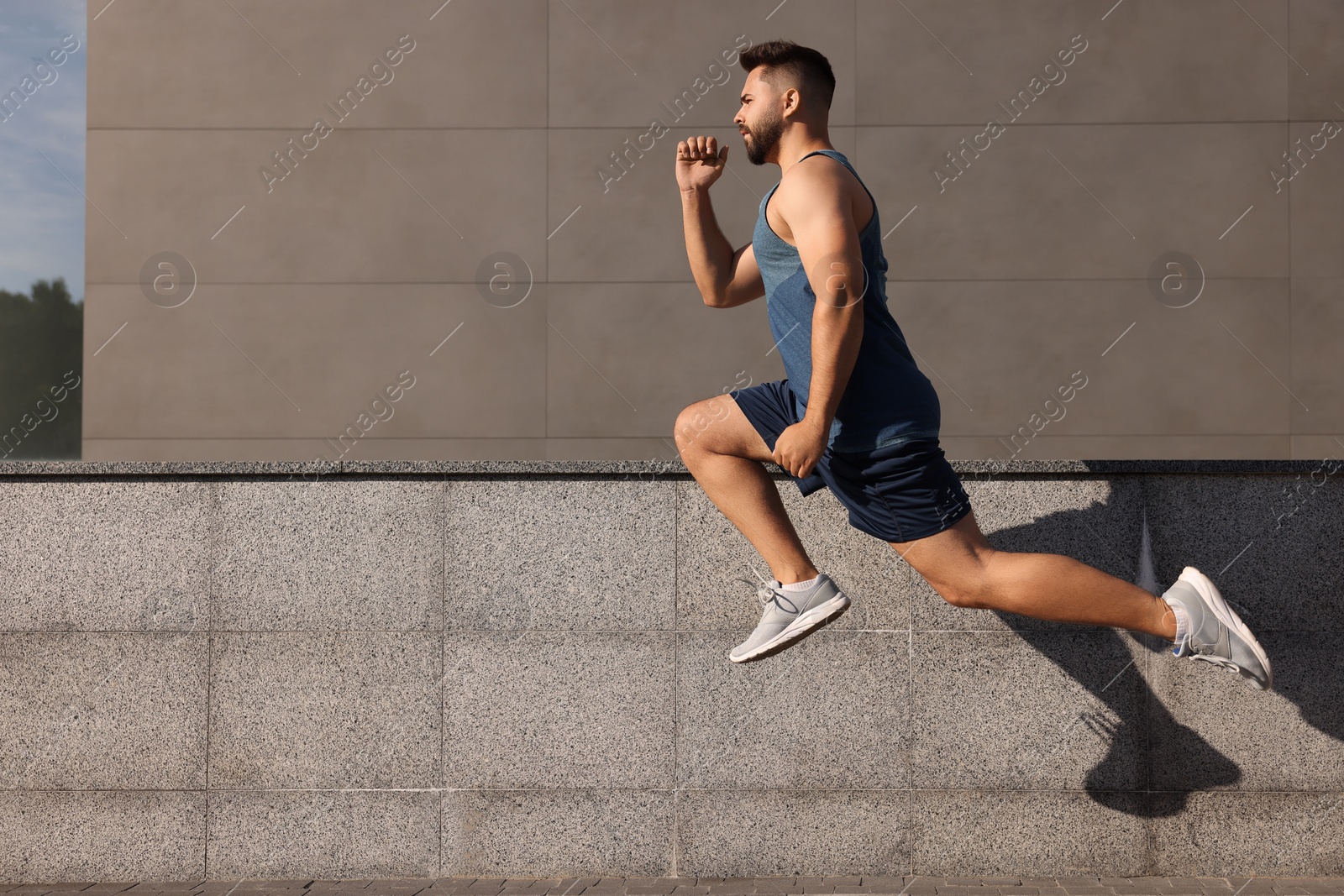 Photo of Young man running near building outdoors. Space for text