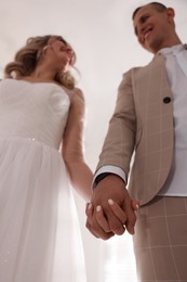 Photo of Bride and groom holding hands together, low angle view