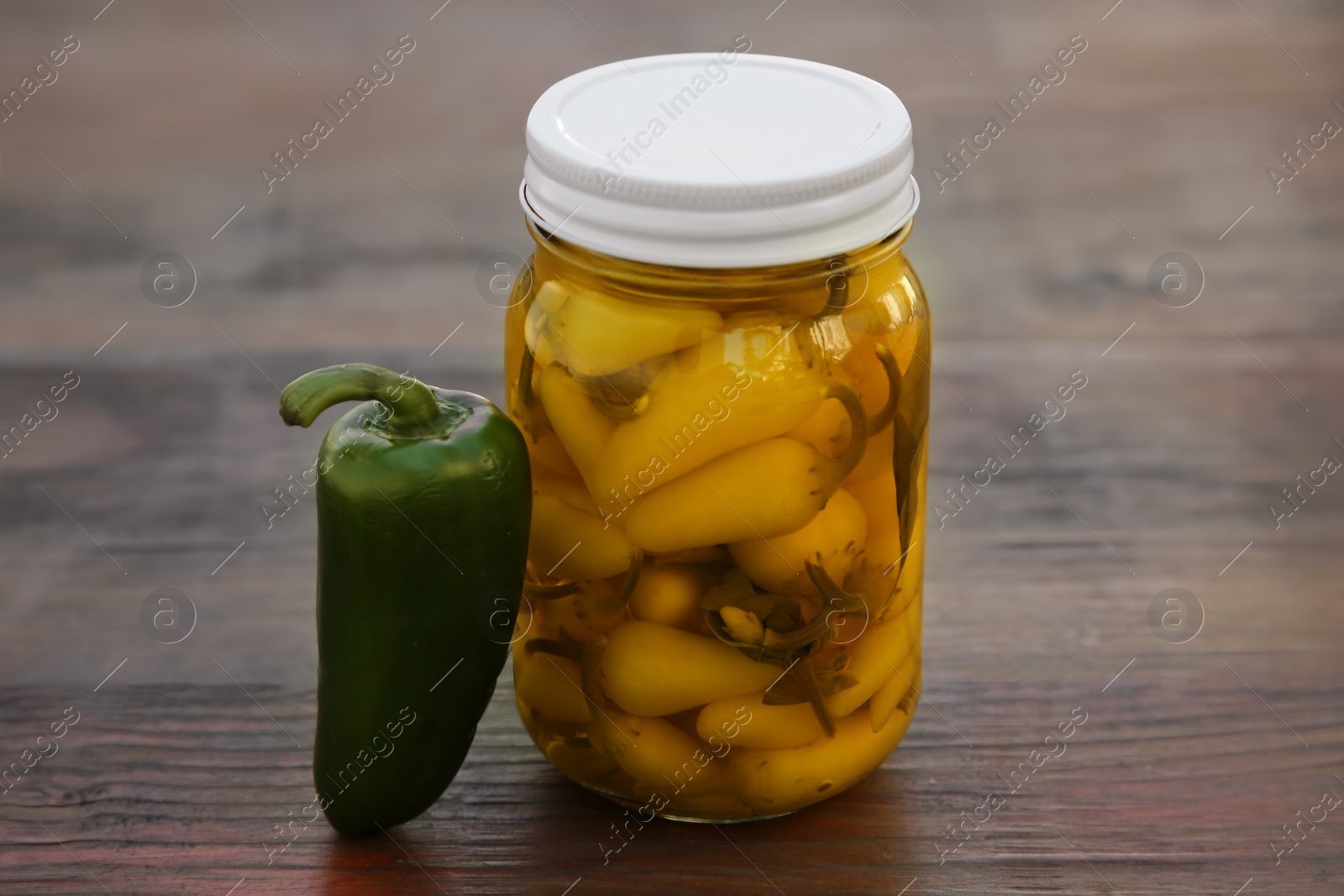 Photo of Fresh and pickled jalapeno peppers on wooden table