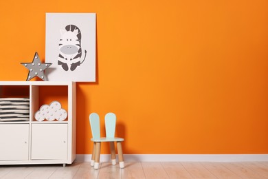 Beautiful children's room with bright orange wall and furniture, space for text. Interior design