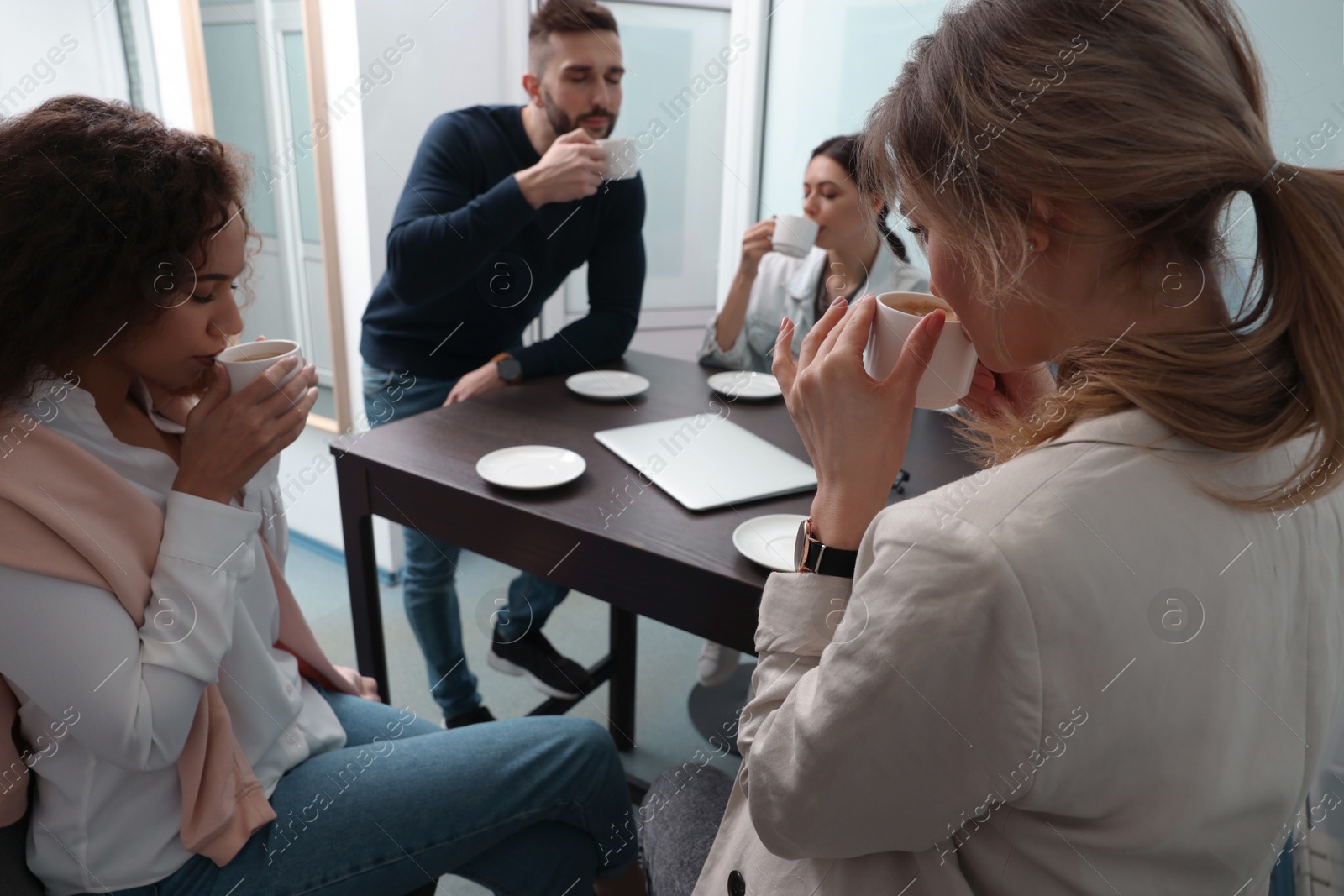 Photo of Team of employees enjoying coffee break together in office. Startup project