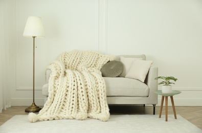 Photo of Knitted merino wool plaid on sofa in room