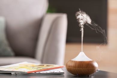 Photo of Aroma oil diffuser lamp on table against blurred background