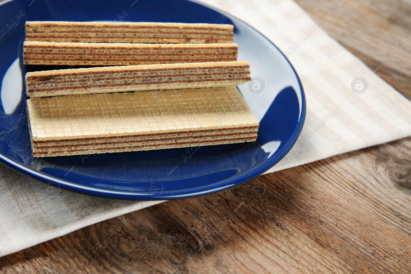 Photo of Plate of delicious wafers on brown wooden background. Space for text