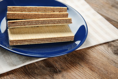 Photo of Plate of delicious wafers on brown wooden background. Space for text