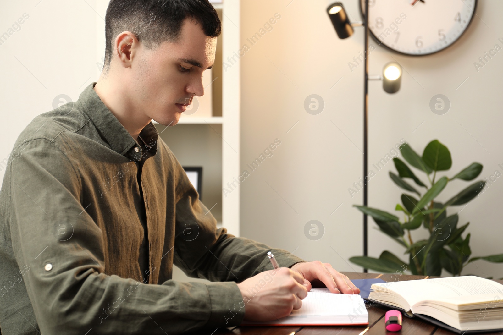 Photo of Man taking notes at wooden table in office