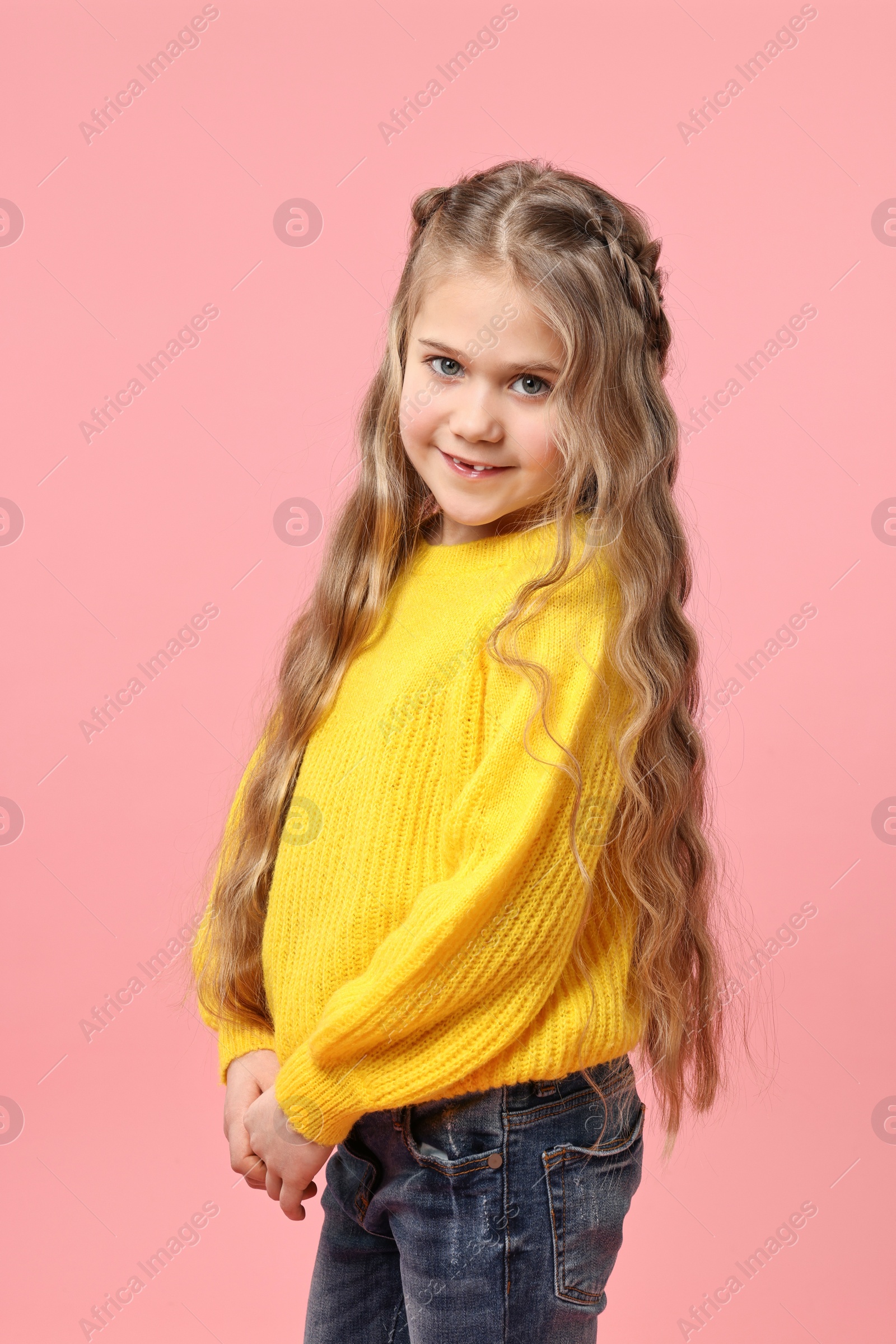 Photo of Cute little girl with braided hair on pink background