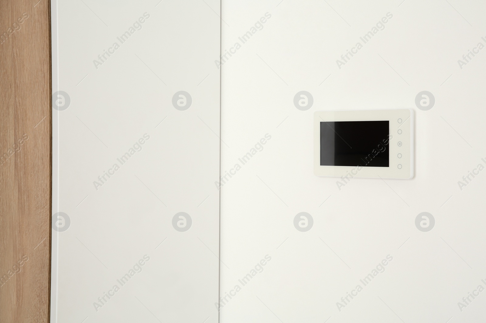 Photo of Modern video intercom hanging on white wall. Space for text