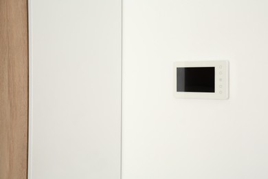 Modern video intercom hanging on white wall. Space for text