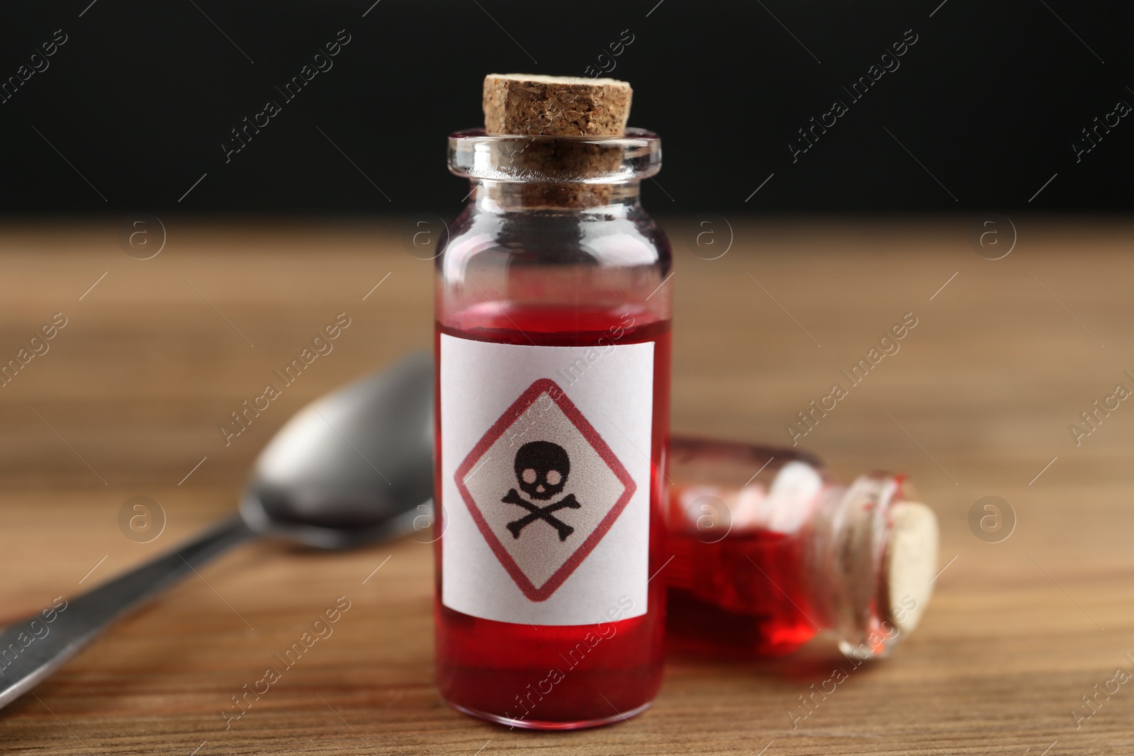 Photo of Vials of poison with spoon on wooden table, closeup