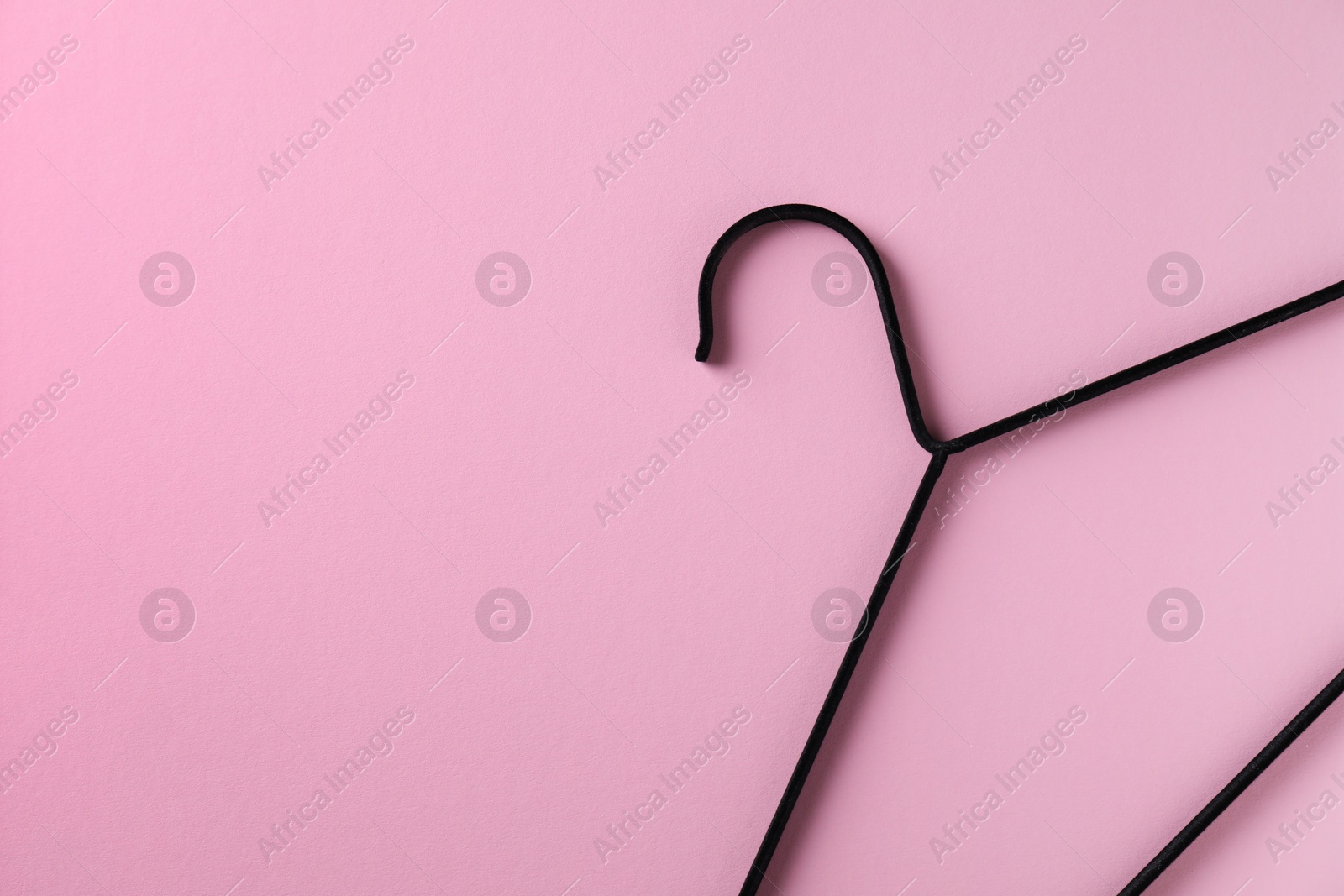 Photo of One black hanger on pink background, top view. Space for text
