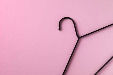 One black hanger on pink background, top view. Space for text