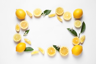 Frame made of lemons, leaves and flowers on white background, top view with space for text. Citrus fruits