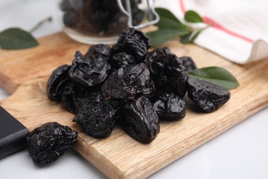 Photo of Tasty dried prunes on light table, closeup view