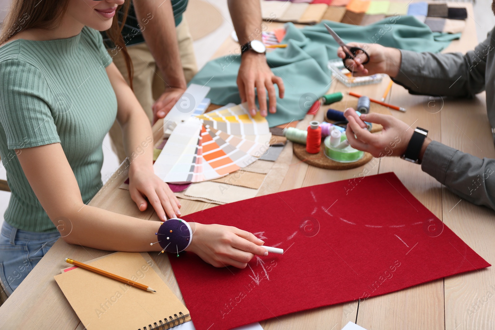 Photo of Fashion designers creating new clothes at table in studio, closeup