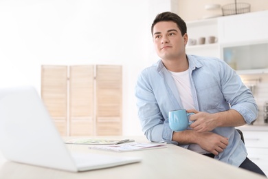 Photo of Portrait of confident young man with  laptop and cup at table