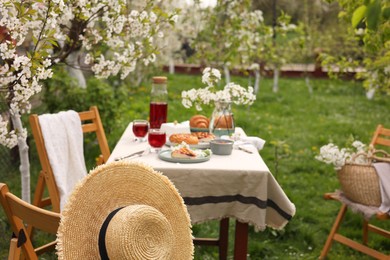 Stylish table setting with beautiful spring flowers, fruit drink and pie in garden