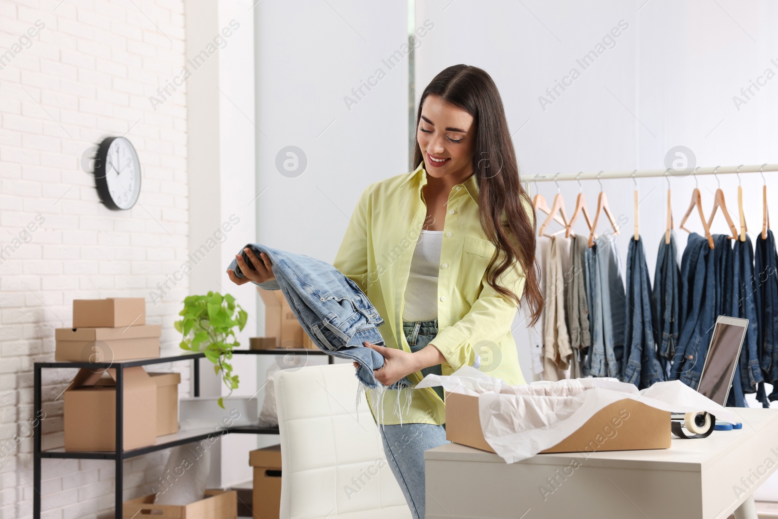 Photo of Seller packing jeans at workplace. Online store