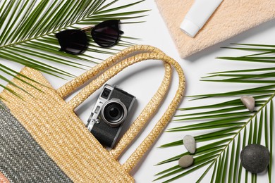Flat lay composition with wicker bag, palm leaves and other beach accessories on white background