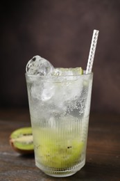 Photo of Glass of refreshing drink and cut kiwi on wooden table, closeup