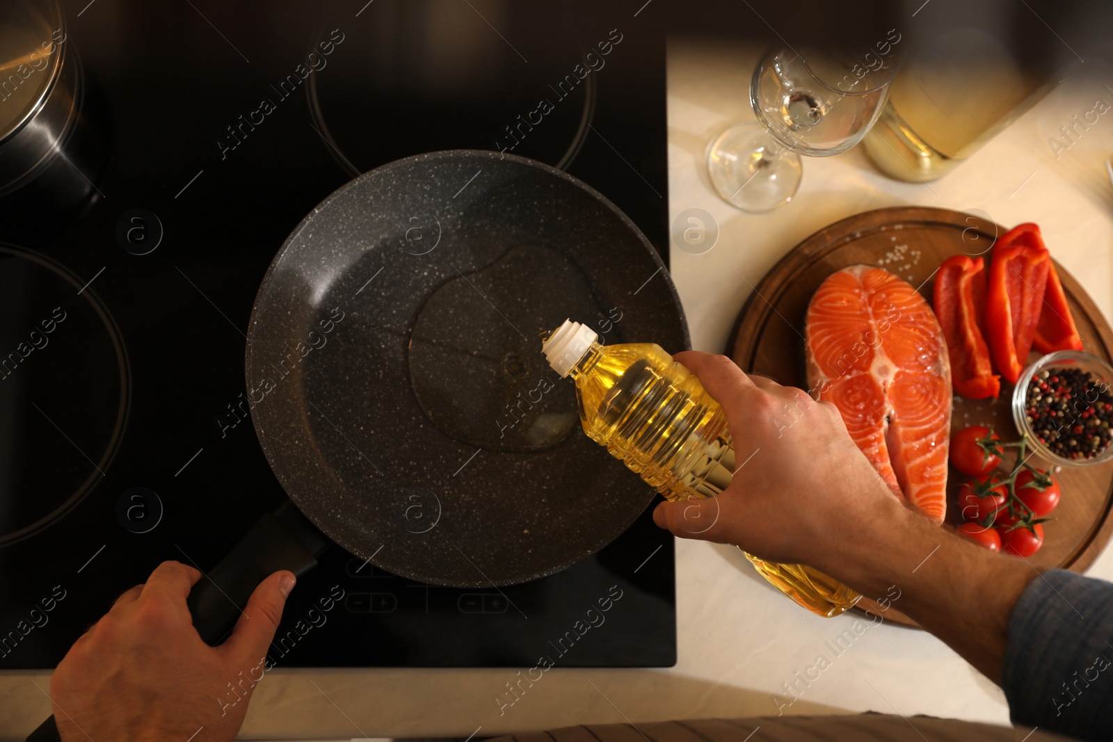 Photo of Man pouring cooking oil into frying pan, top view
