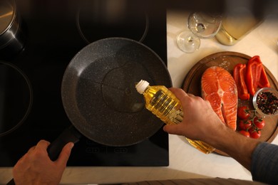 Photo of Man pouring cooking oil into frying pan, top view