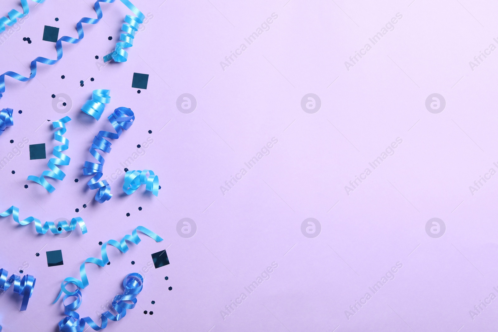 Photo of Blue serpentine streamers and confetti on light background, flat lay. Space for text