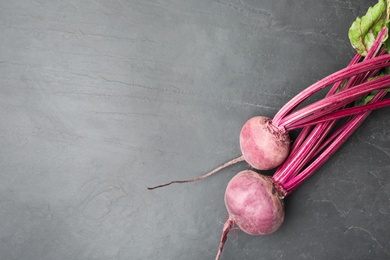 Raw ripe beets on black slate table, flat lay. Space for text