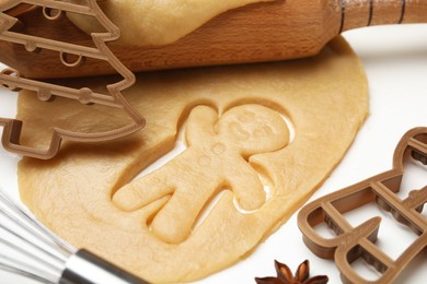 Photo of Christmas treat. Cookie cutters, dough and rolling pin on white table, closeup
