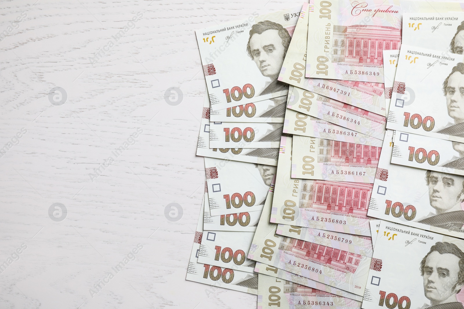 Photo of Ukrainian money on white wooden background, flat lay. Space for text