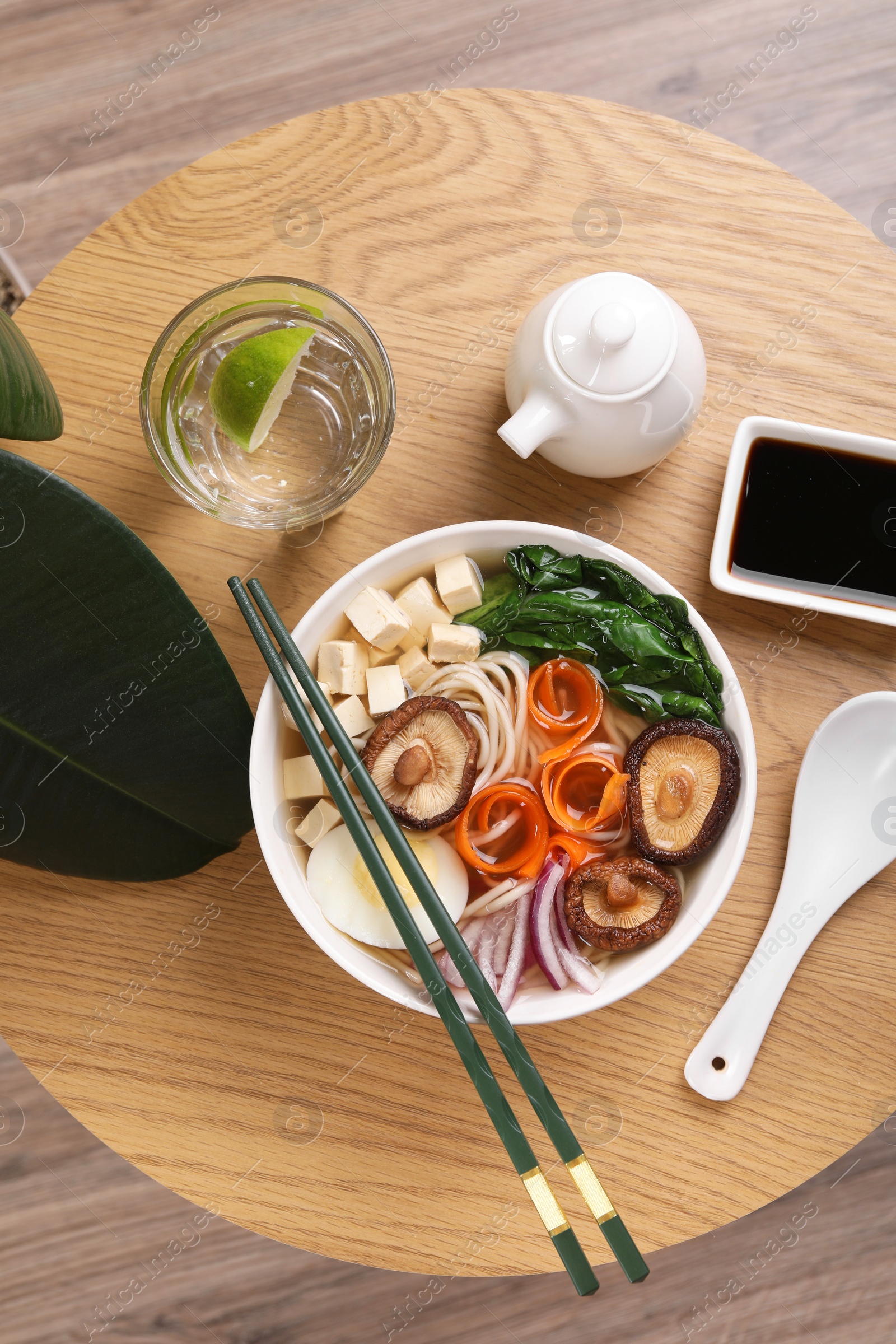 Photo of Delicious vegetarian ramen served on wooden table, flat lay. Noodle soup