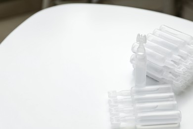 Photo of Single dose ampoules of sterile isotonic sea water solution on white table. Space for text