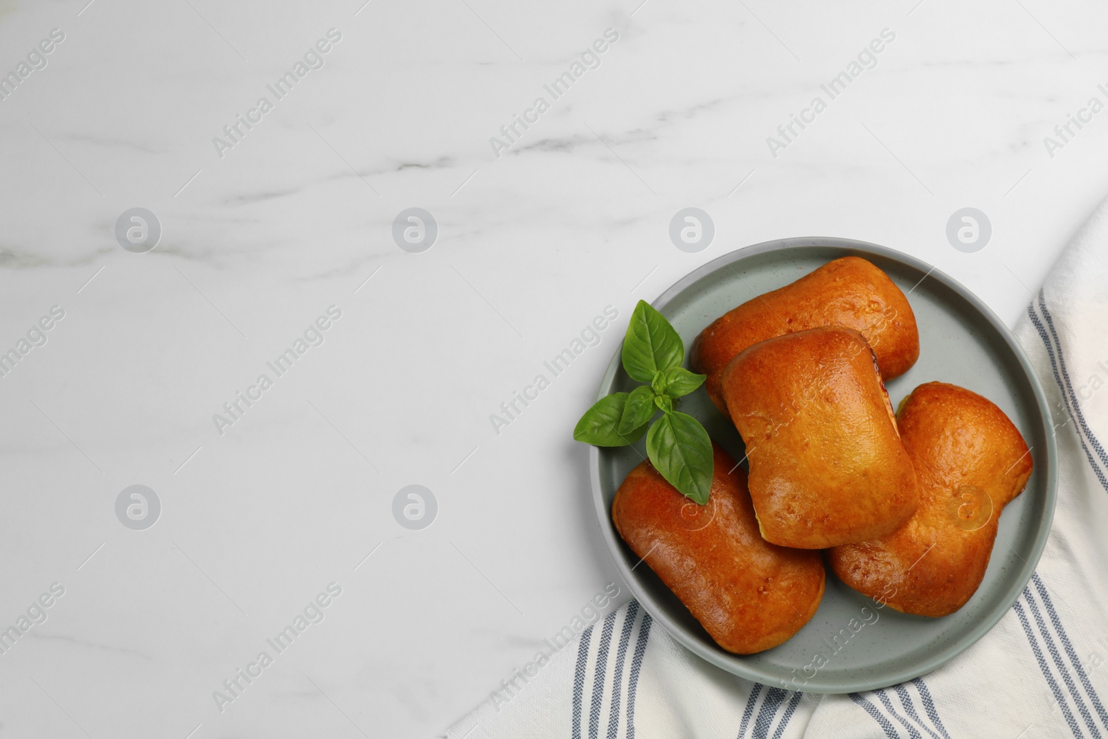Photo of Delicious baked patties and basil on white table, top view. Space for text