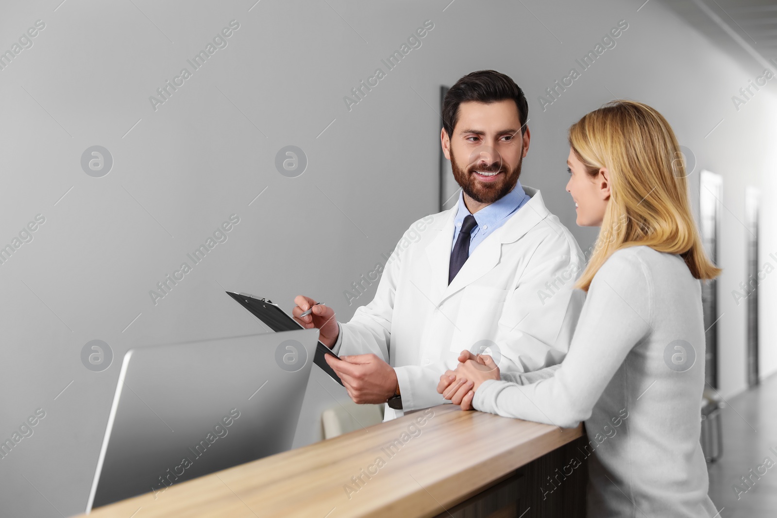 Photo of Doctor with clipboard consulting patient in clinic