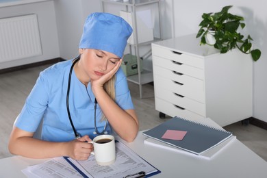 Photo of Tired young doctor sleeping at workplace in office
