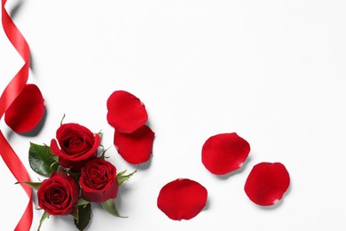 Photo of Beautiful red roses, petals and ribbon on white background, top view. Space for text